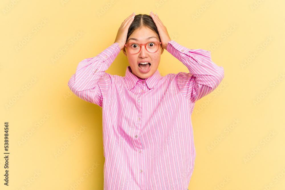 Young Asian woman isolated on yellow background screaming, very excited, passionate, satisfied with something. Young Asian woman isolated on yellow background screaming, very excited, passionate, satisfied with something.