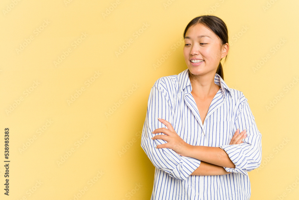Young Asian woman isolated on yellow background smiling confident with crossed arms. Young Asian woman isolated on yellow background smiling confident with crossed arms.