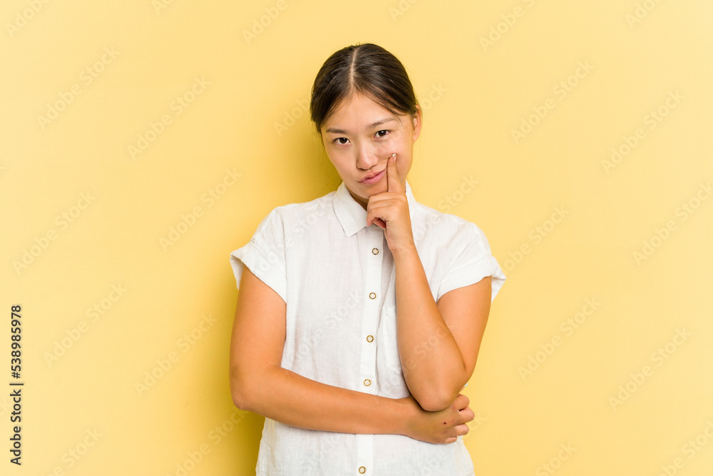 Young Asian woman isolated on yellow background contemplating, planning a strategy, thinking about the way of a business. Young Asian woman isolated on yellow background contemplating, planning a strategy, thinking about the way of a business.
