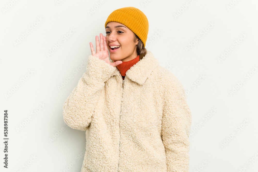 Young Indian woman wearing winter jacket isolated on white background shouting and holding palm near opened mouth.
