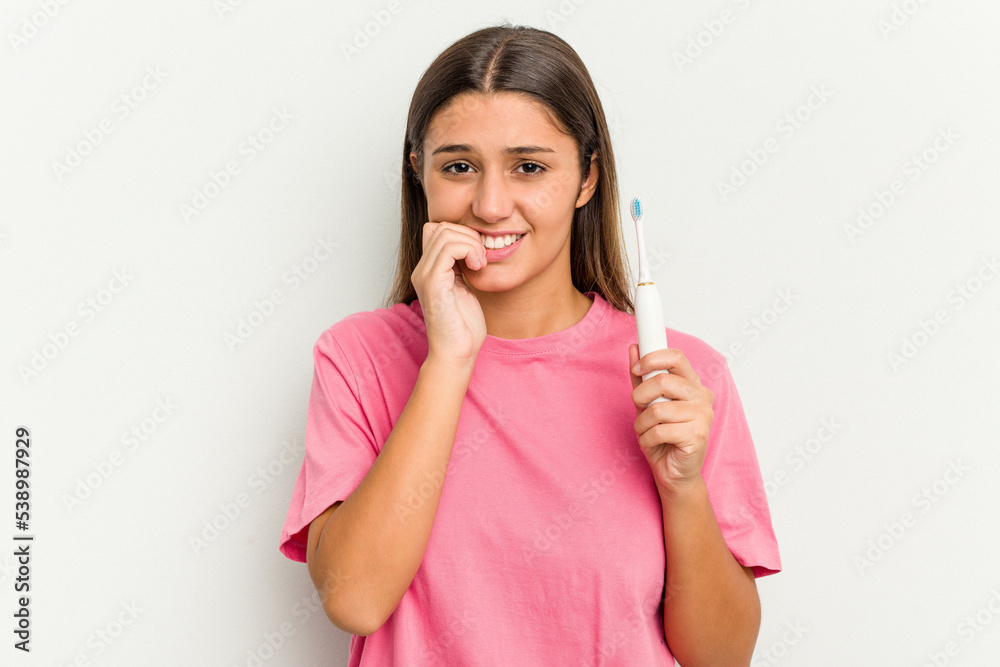 Young Indian woman brushing teeth isolated on white background biting fingernails, nervous and very anxious.