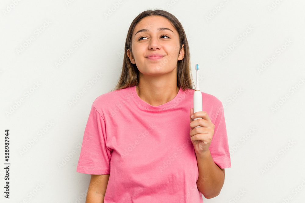 Young Indian woman brushing teeth isolated on white background dreaming of achieving goals and purposes Young Indian woman brushing teeth isolated on white background dreaming of achieving goals and purposes
