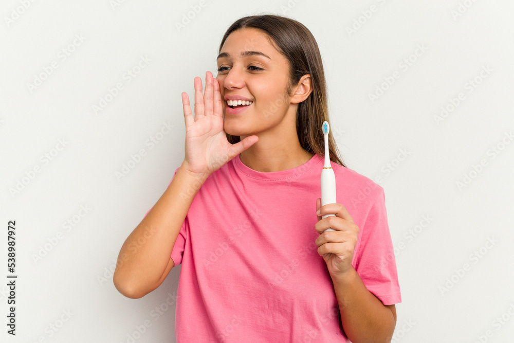 Young Indian woman brushing teeth isolated on white background shouting and holding palm near opened mouth. Young Indian woman brushing teeth isolated on white background shouting and holding palm near opened mouth.