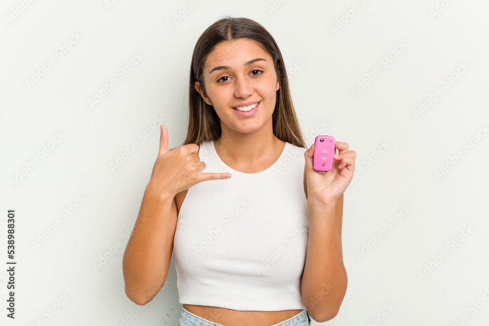 Young indian woman holding an electronic pink car keys showing a mobile phone call gesture with fingers. Young indian woman holding an electronic pink car keys showing a mobile phone call gesture with fingers.