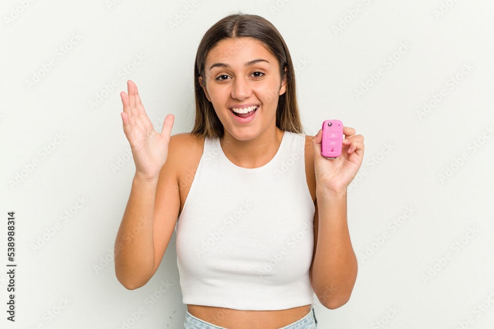Young indian woman holding an electronic pink car keys receiving a pleasant surprise, excited and raising hands. Young indian woman holding an electronic pink car keys receiving a pleasant surprise, excited and raising hands.