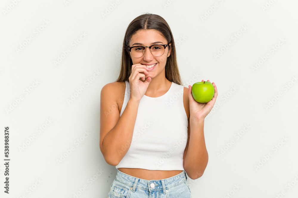 Young Indian woman holding an apple isolated on white background biting fingernails, nervous and very anxious. Young Indian woman holding an apple isolated on white background biting fingernails, nervous and very anxious.