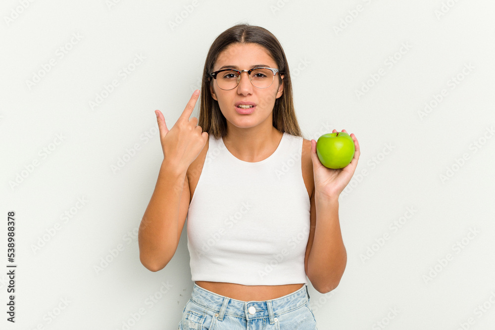 Young Indian woman holding an apple isolated on white background showing a disappointment gesture with forefinger. Young Indian woman holding an apple isolated on white background showing a disappointment gesture with forefinger.