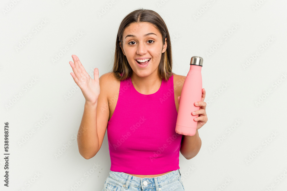 Young indian woman holding a pink thermo isolated on white background receiving a pleasant surprise, excited and raising hands. Young indian woman holding a pink thermo isolated on white background receiving a pleasant surprise, excited and raising hands.