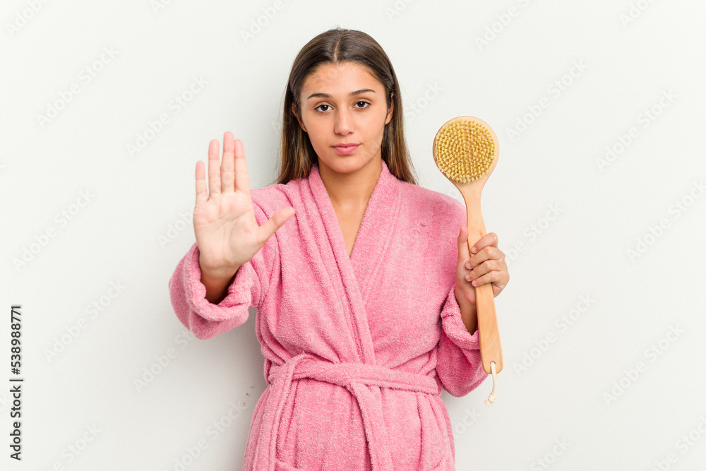 Young Indian woman holding a shower brush isolated on white background standing with outstretched hand showing stop sign, preventing you. Young Indian woman holding a shower brush isolated on white background standing with outstretched hand showing stop sign, preventing you.