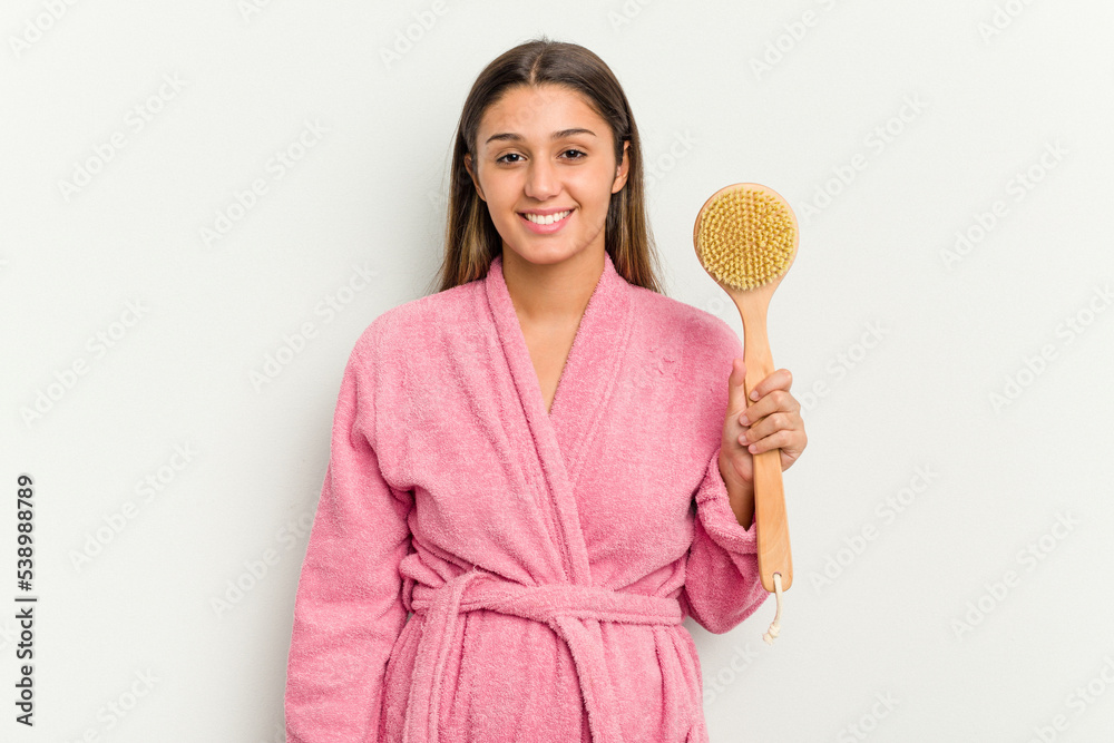 Young Indian woman holding a shower brush isolated on white background happy, smiling and cheerful. Young Indian woman holding a shower brush isolated on white background happy, smiling and cheerful.