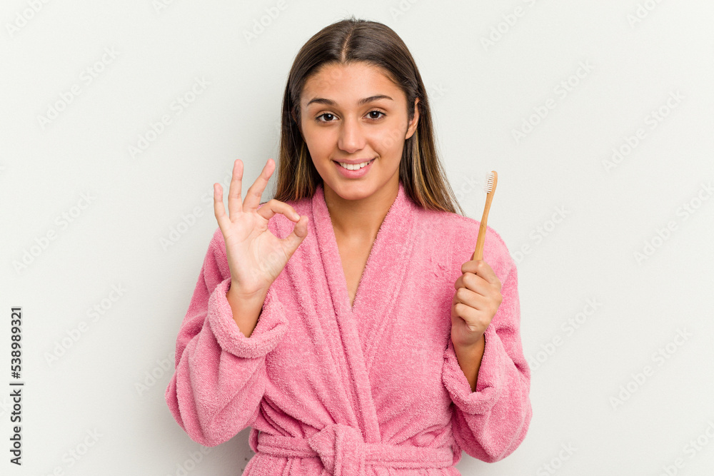 Young Indian woman brushing teeth isolated on white background cheerful and confident showing ok gesture. Young Indian woman brushing teeth isolated on white background cheerful and confident showing ok gesture.