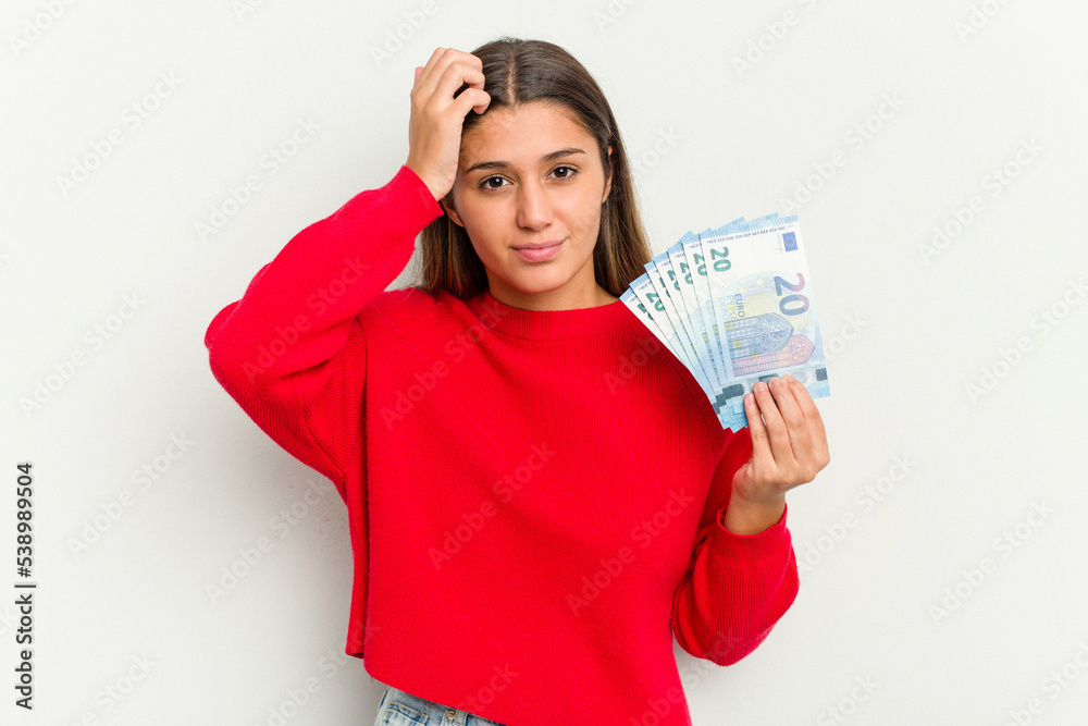 Young Indian woman holding a banknotes isolated on white background being shocked, she has remembered important meeting. Young Indian woman holding a banknotes isolated on white background being shocked, she has remembered important meeting.