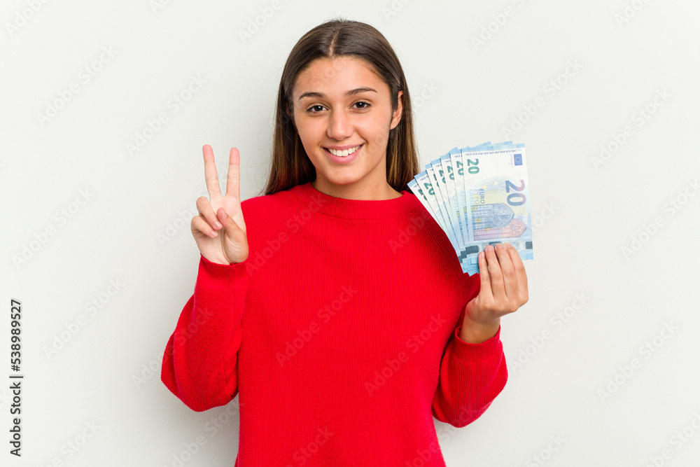 Young Indian woman holding a banknotes isolated on white background showing number two with fingers. Young Indian woman holding a banknotes isolated on white background showing number two with fingers.