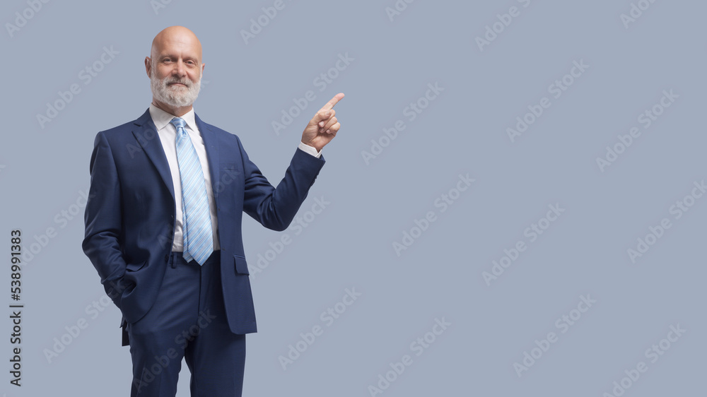 Confident businessman pointing and smiling Confident businessman pointing and smiling