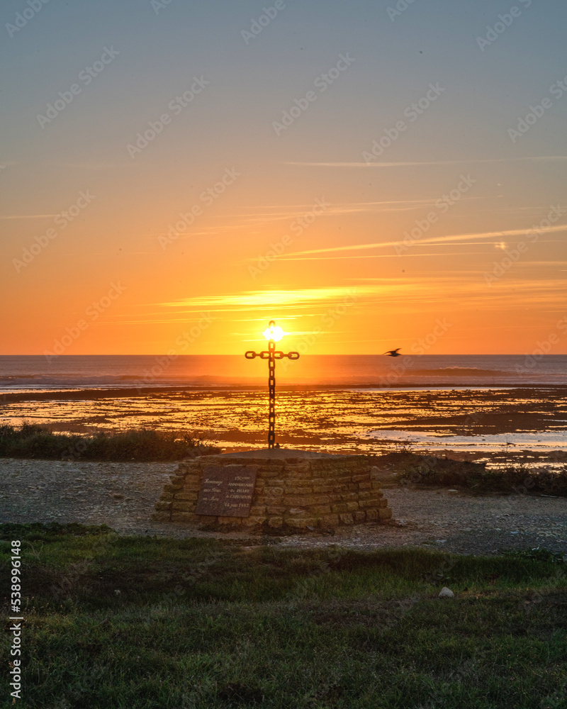coucher de soleil sur l'île d'Oléron près des falaises et phare de Chassiron au bord de l'océan avec la croix érigée en hommage aux morts en mer