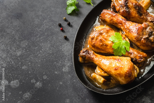 Drumsticks air fryer chicken legs in cast iron skillet on dark background. Top view, copy space.