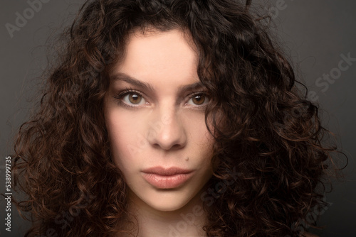 portrait of woman with thick lips and curly hair looking at camera