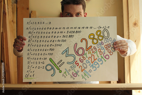 Drawing with colourful numbers in the hands of a young man. Pavel, i and my drawing with colourful factorial numbers in my hands. Photo was taken 19 July 2022 year, MSK time in Russia. photo