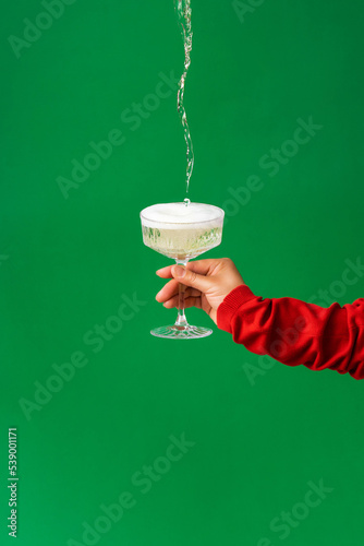 Trendy festive background, stream of champagne, wine pours from above into glass in female hand
