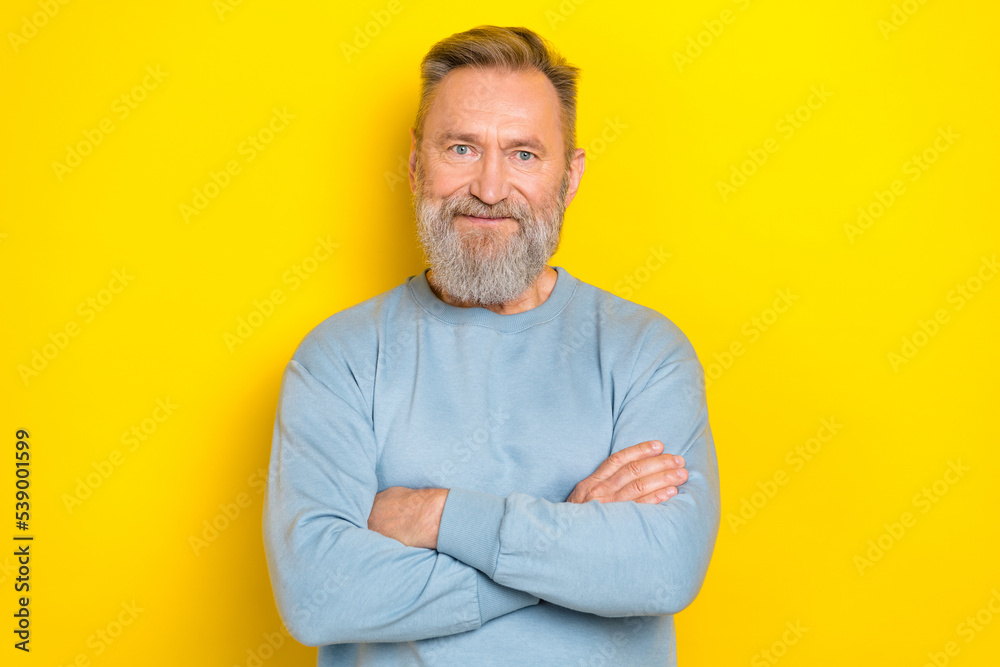 Photo of confident charming retired guy wear blue sweater arms crossed smiling isolated yellow color background