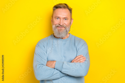 Photo of confident charming retired guy wear blue sweater arms crossed smiling isolated yellow color background
