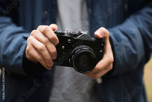 person holding retro metal camera and adjusting settings