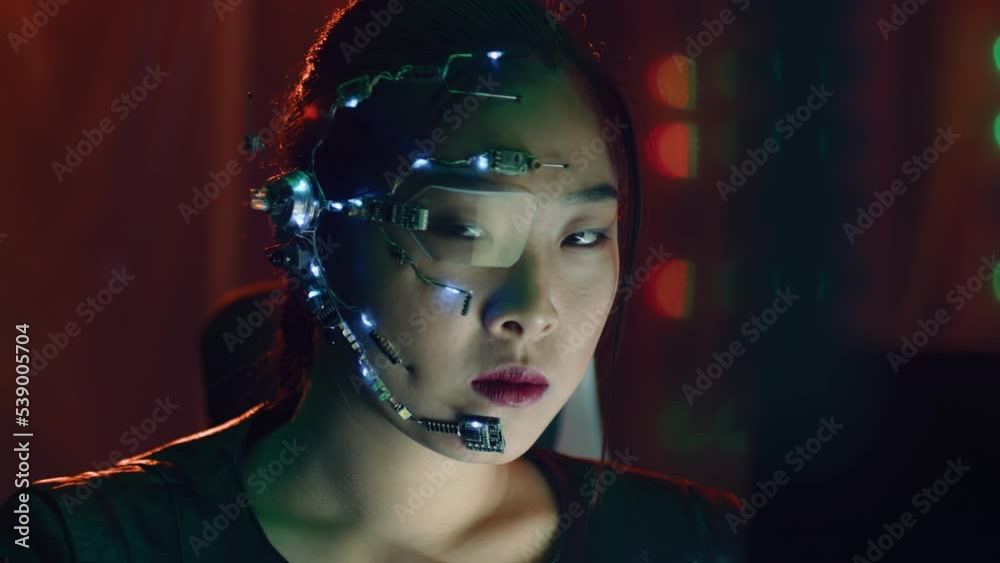 A Cyberpunk girl looks at the computer screen. Wearing futuristic one-eyed glasses with microphone. Stops looking at the computer to face the camera. Cyber and sci-fi backgrounds. A Cyberpunk girl looks at the computer screen. Wearing futuristic one-eyed glasses with microphone. Stops looking at the computer to face the camera. Cyber and sci-fi backgrounds.