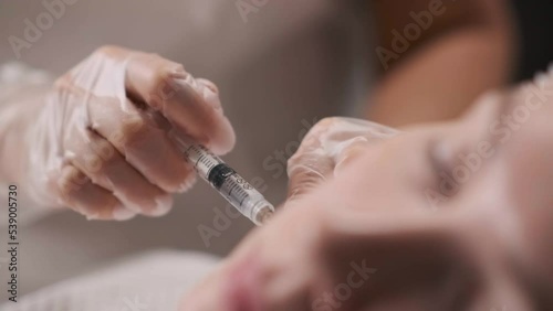 Cosmetology. A doctor in transparent gloves gives the patient injections in the face photo