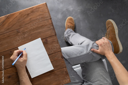 Man writing on notebook at table thinking idea solution. Study or design creative concept