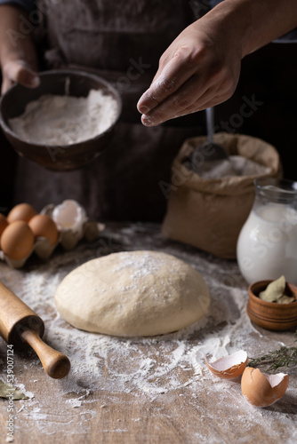 Baker chef man sprinkling flour at dough bread and bakery ingredients for homemade cooking on table