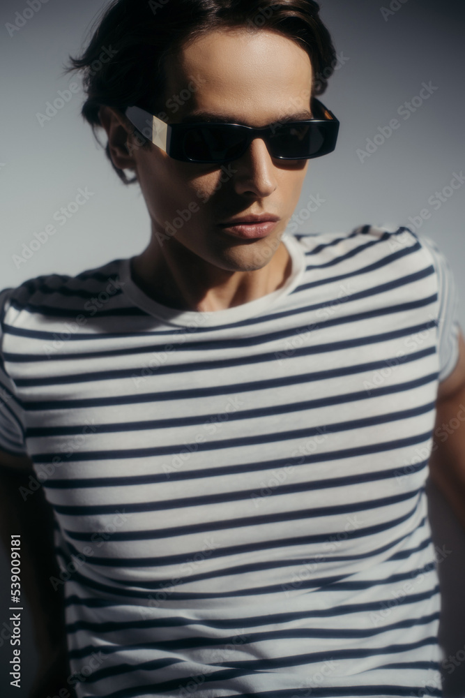Fashionable man in sunglasses on grey background with lighting Fashionable man in sunglasses on grey background with lighting