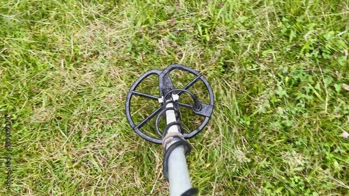 Man with metal detector is moving from side to side on the field for metal seeking. Treasure hunt concept.Search for treasure with electronic metal detector device on the grass 