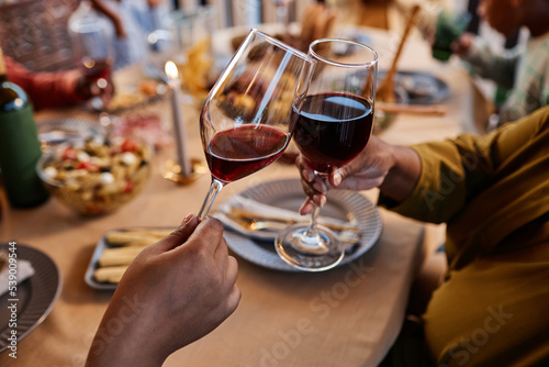 Close up of black couple clinking wine glasses at dinner table outdoors in cozy setting
