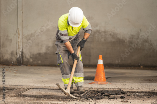 Worker working with a pickaxe in front of an orange cone