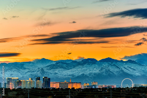 Las Vegas skyline in winter snow capped mountain and a jet plane taking off in the sunset sky