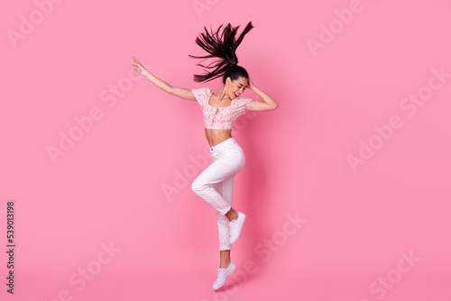 Full body profile photo of sweet young brunette lady jump wear crop top jeans shoes isolated on pink background