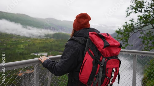 Travel woman stands on the edge of a cliff at the voringfossen waterfall Feeling completely free