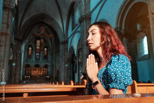The girl prays in the Catholic Church and asks God for health, forgiveness of sins and finding spiritual peace