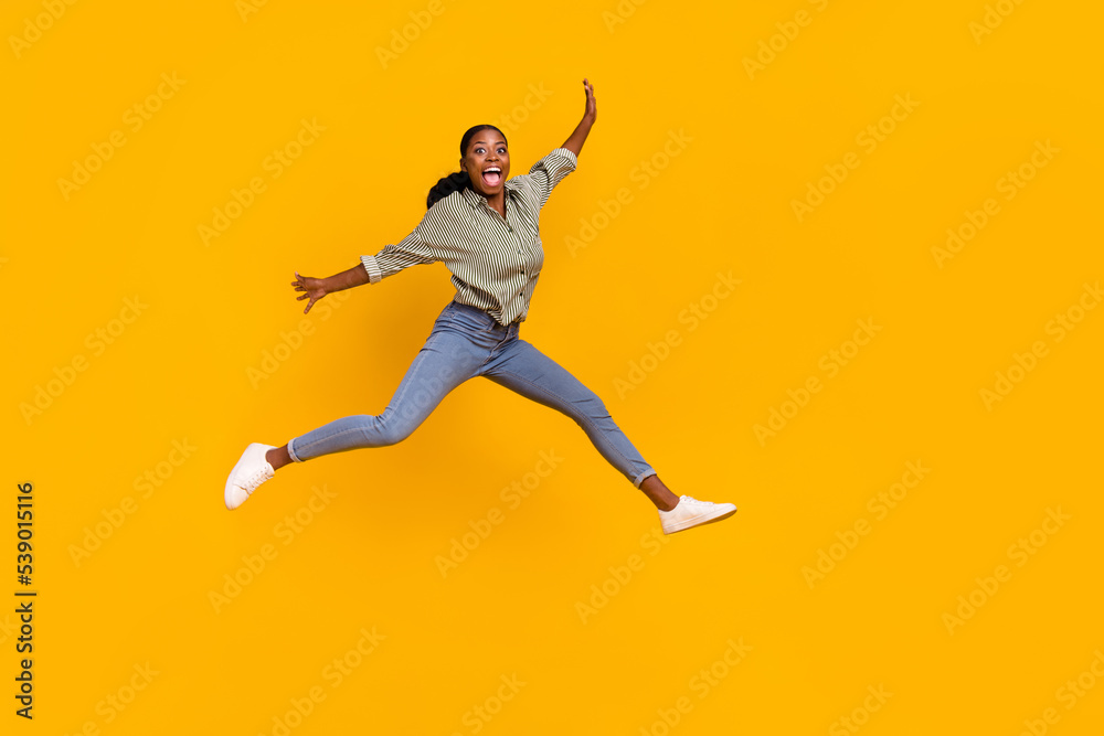 Full length photo of satisfied person jumping raise hands open mouth isolated on yellow color background