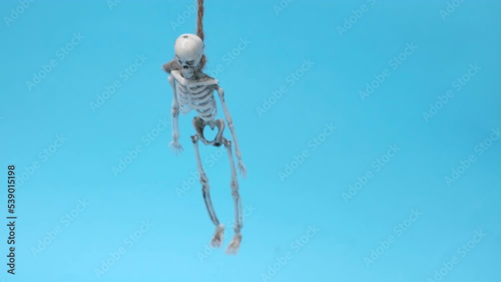 skeleton hanging on gallows over blue background. Halloween video with