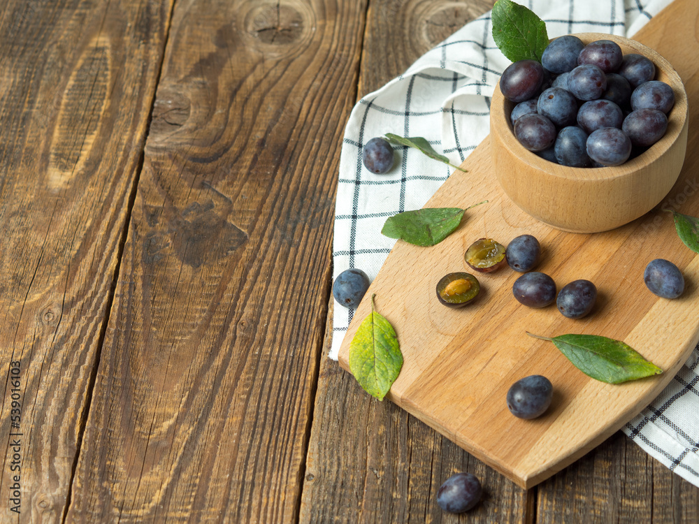 Blue plum in a bowl on a wooden table. Fruit background with copy space. Blue plum in a bowl on a wooden table. Fruit background with copy space.
