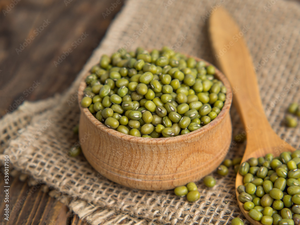 Close-up mung beans .Green mung beans in a wooden bowl on an old table Close-up mung beans .Green mung beans in a wooden bowl on an old table