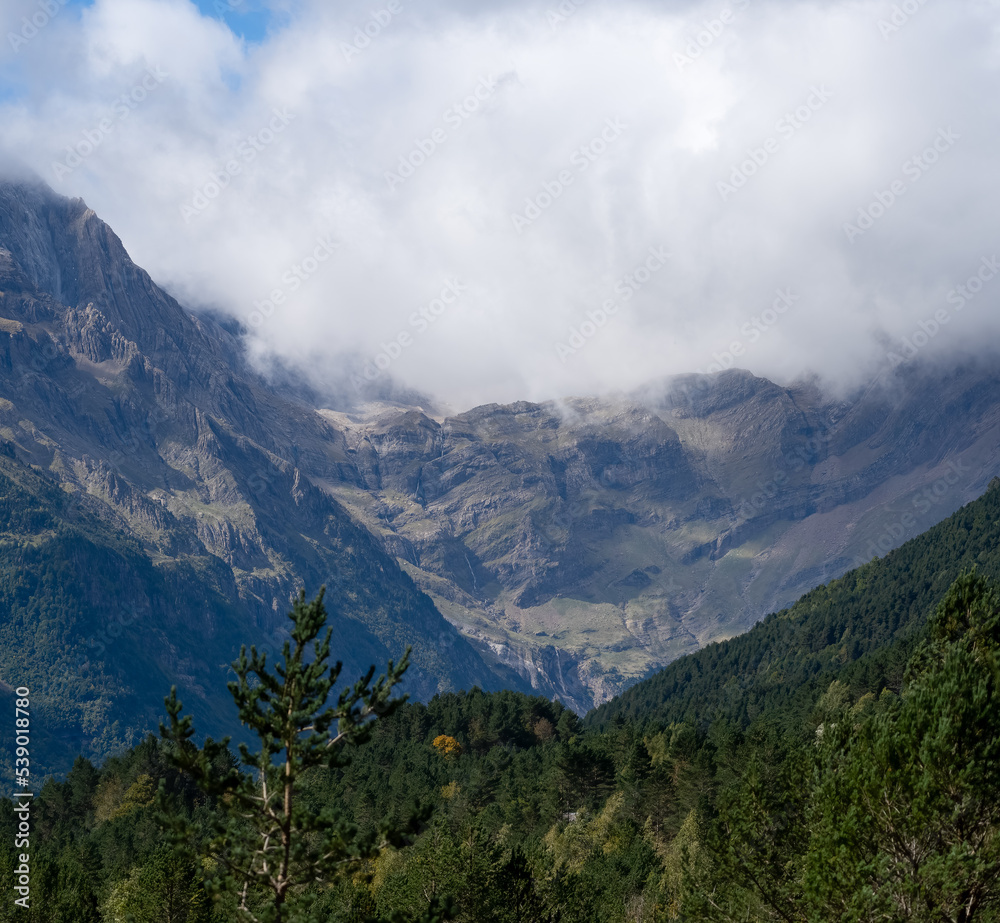 Obraz premium magnificent view of a long glacial forested valley through cloud topped Spanish Pyrenees mountains