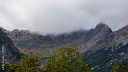 magnificent view of a long glacial forested valley through cloud topped Spanish Pyrenees mountains