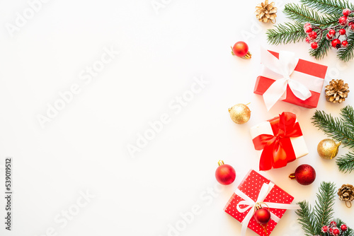 Christmas holiday decorations at white background with copy space. Gift boxes, fir tree, baubles and others. Flat lay composition.