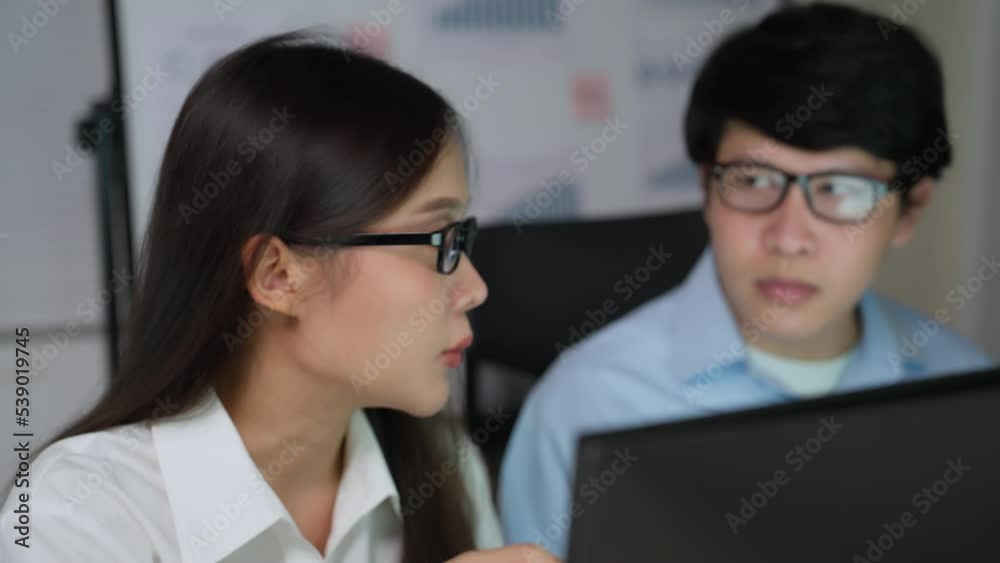 Asian young business people using computer to work together at office. They talk work together share ideas on digital marketing strategy at office meeting.