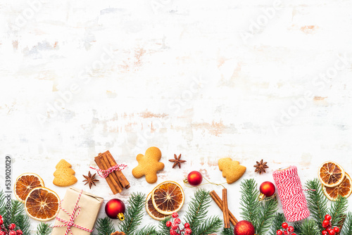 Christmas background with gingerbread, spices and holiday decorations with fir tree on white. Flat lay composition with copy space.