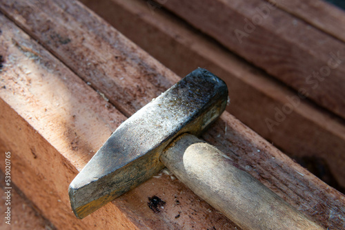 a hammer used to work the wood needed for a wooden structure, an old hammer lying on wooden red preserved beams