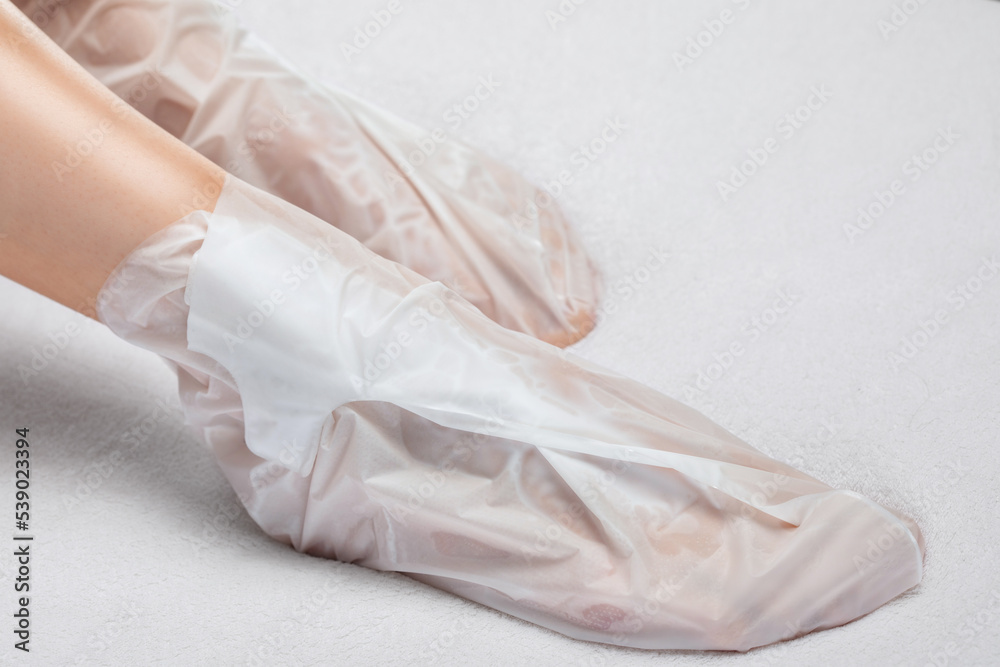A woman makes a mask on the feet against dryness, cracked skin on the heels and against fatigue with a spa salon. A woman makes a mask on the feet against dryness, cracked skin on the heels and against fatigue with a spa salon.