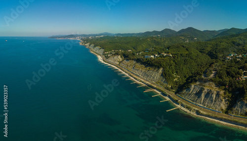 over the Black Sea beaches near the green Caucasian mountains near the village of Dederkoy in the South of Russia. Concrete breakwaters along the edge of the sea and the port of Tuapse on the horizon